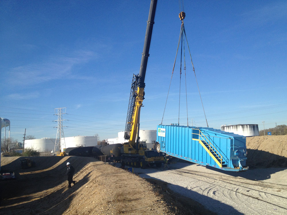 Crane lifting E-Tank frac tank at industrial site, demonstrating safe tank handling and environmental equipment rental procedures