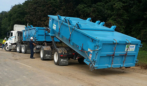 E-Tank roll-off boxes being safely loaded onto a truck for transport, illustrating vacuum sludge dewatering and roll-off box handling procedures