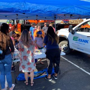 Families visiting the E-Tank booth at a community Touch-a-Truck event, learning about environmental equipment rental and liquid storage solutions
