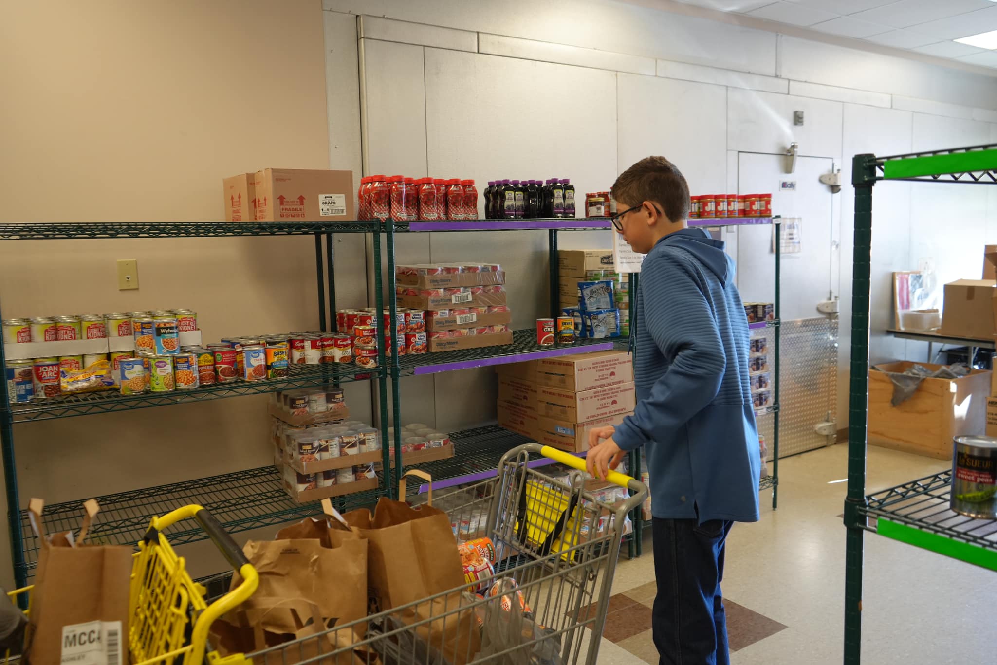Young volunteer helping organize canned goods and donations on pantry shelves during E-Tank Thanksgiving food drive